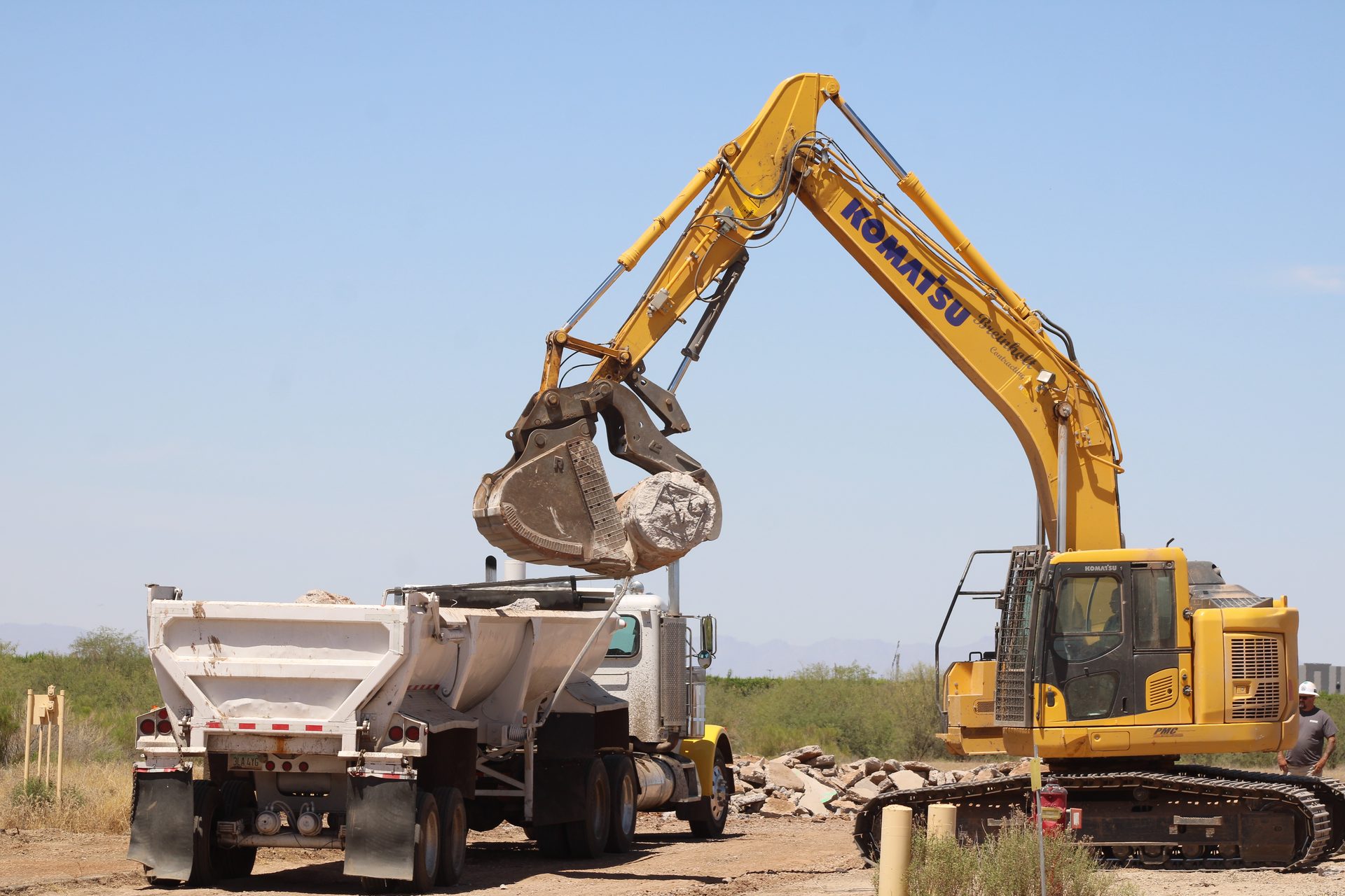 Komatsu excavator loading crushed concrete into a haul truck