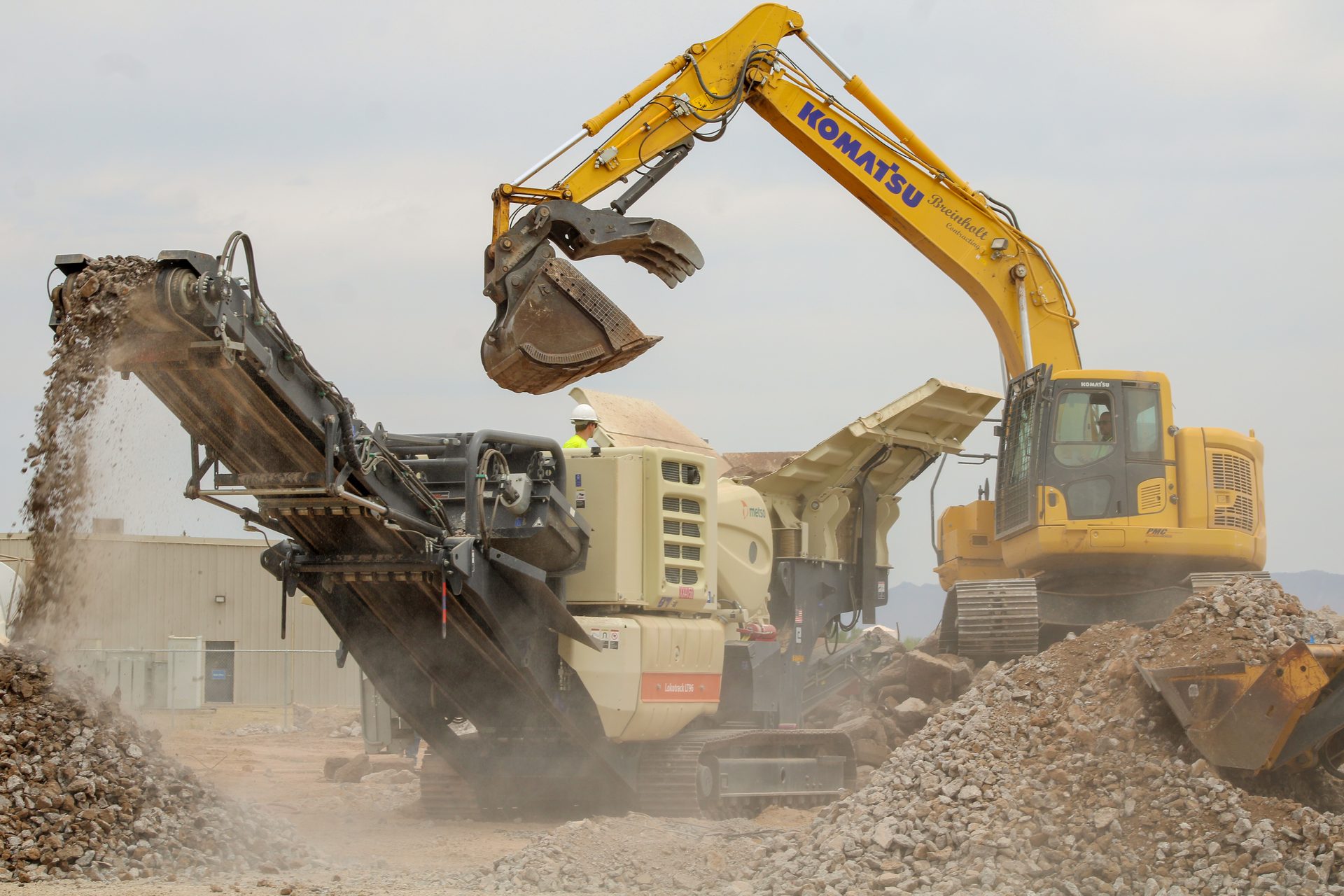 Excavator feeding demolition debris into a portable rock crusher